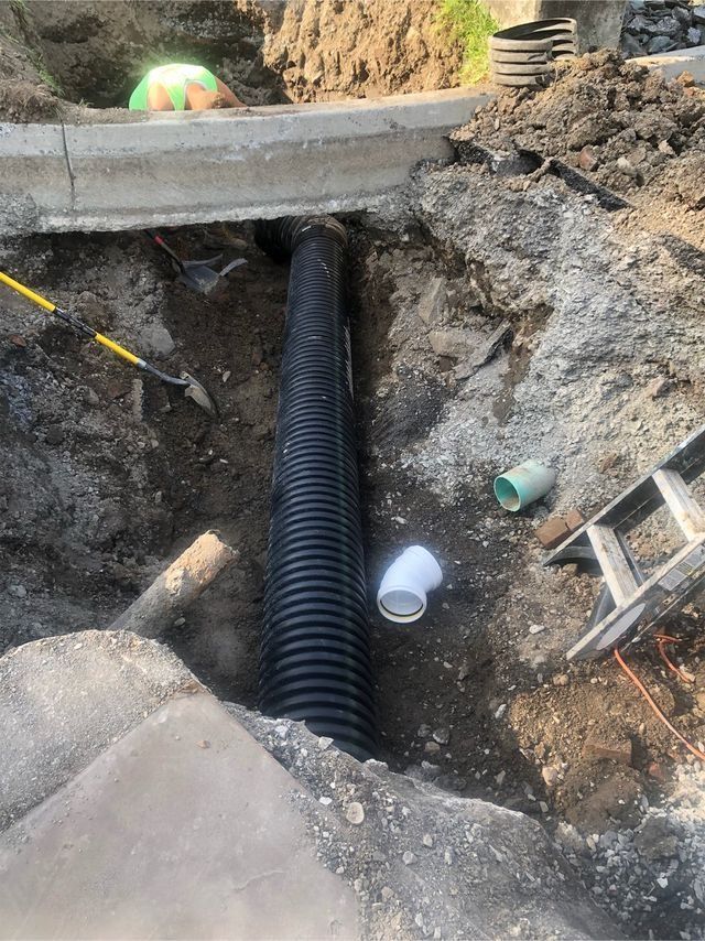 a drain pipe is being installed in a hole in the ground .