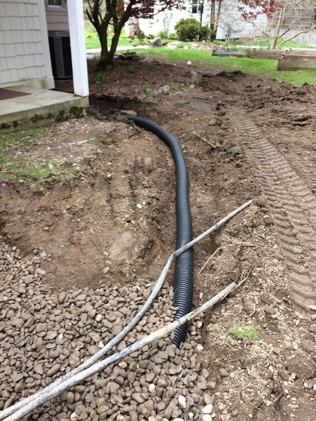 a black pipe is laying in the dirt next to a house .