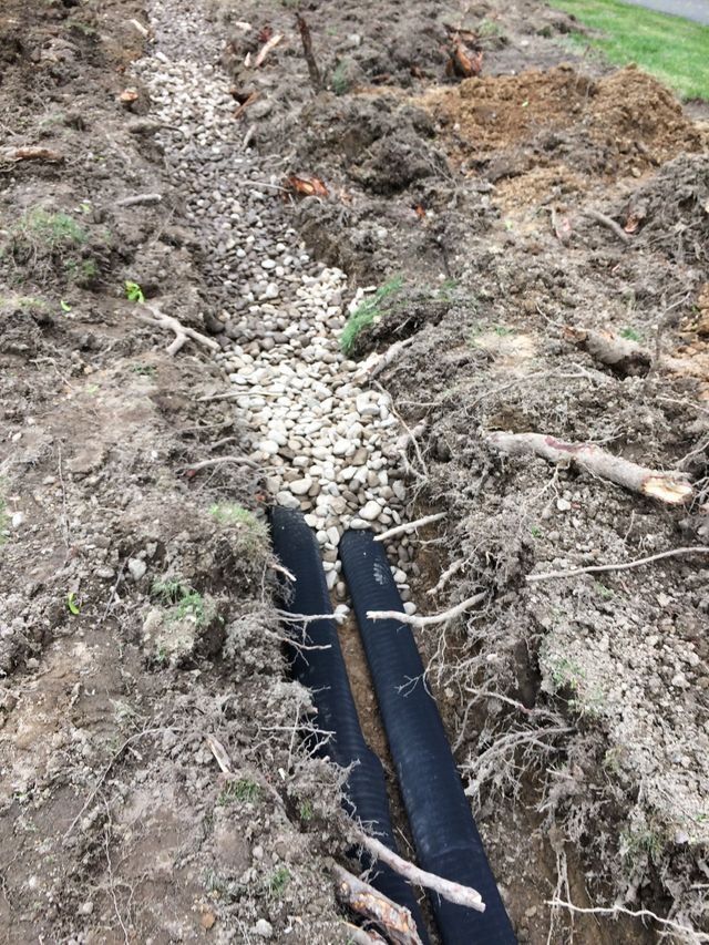 a black pipe is laying in the dirt in a trench .