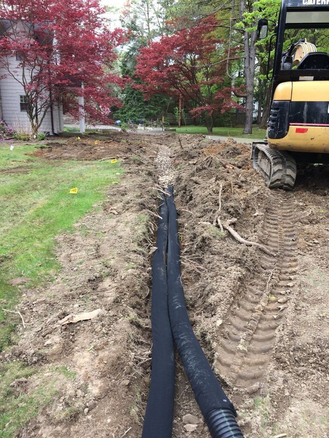 an excavator is digging a hole in the ground in front of a house .
