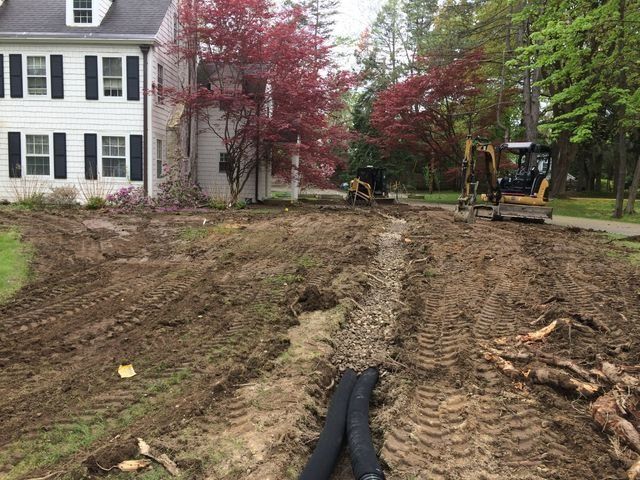 a bulldozer is moving dirt in front of a house .