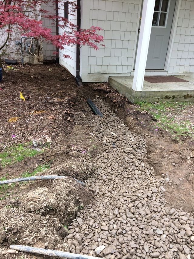 a person is digging a hole in the dirt in front of a house .