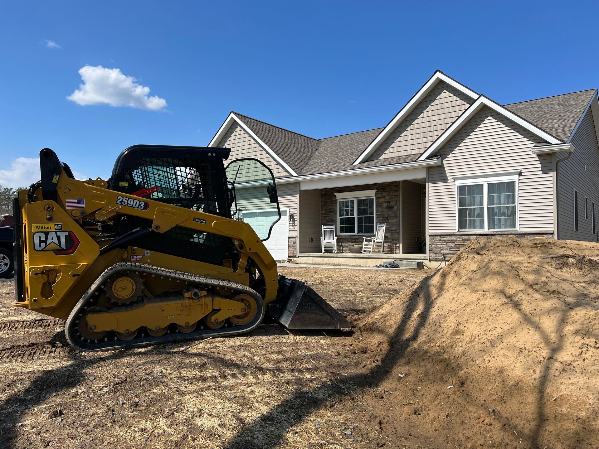 a bulldozer is moving dirt in front of a house .