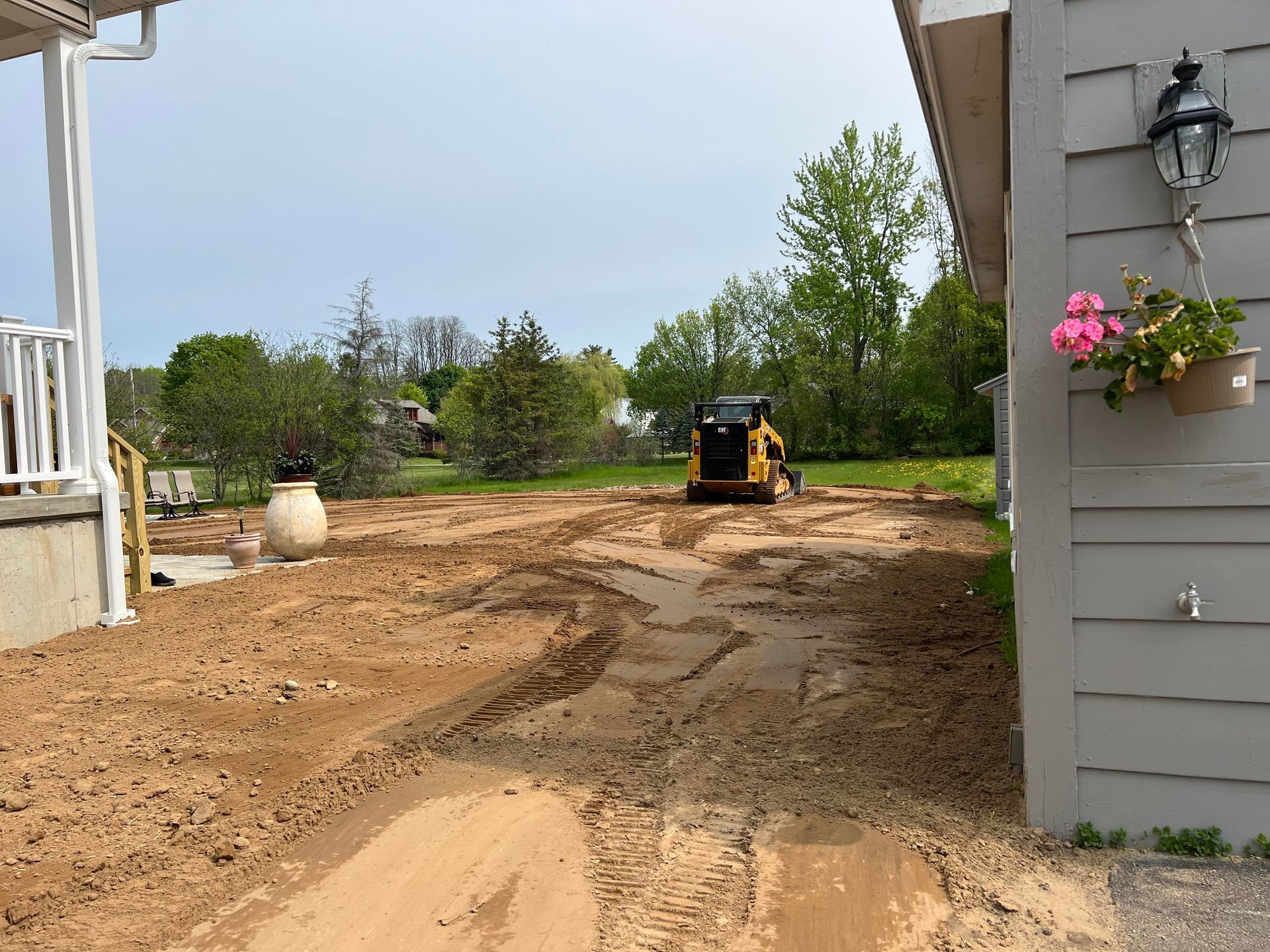 a bulldozer is sitting on a residential lot next to a new house .