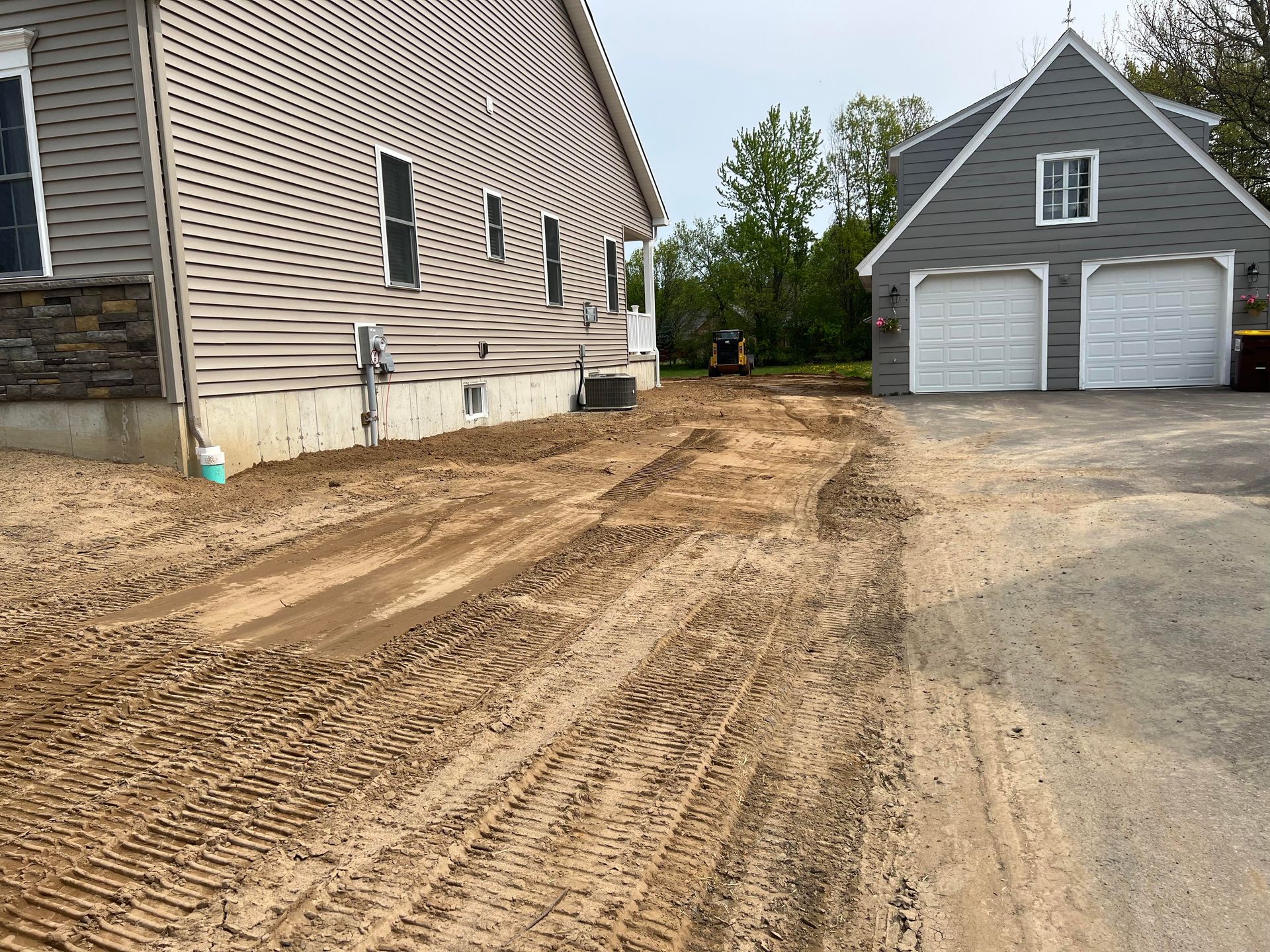 a newly built house with a garage and a dirt lot .