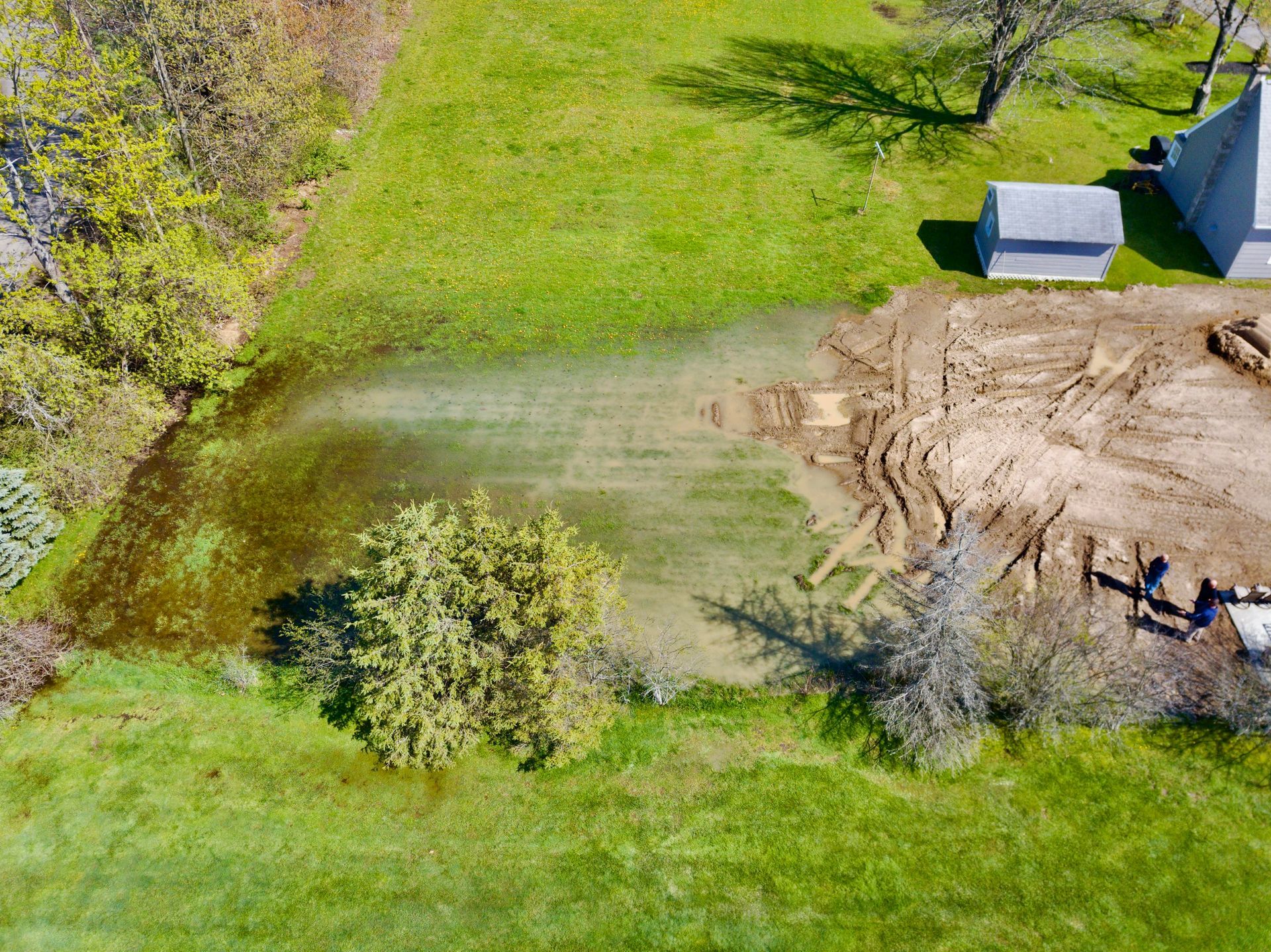 an aerial view of a lush green field with a pond in the middle .