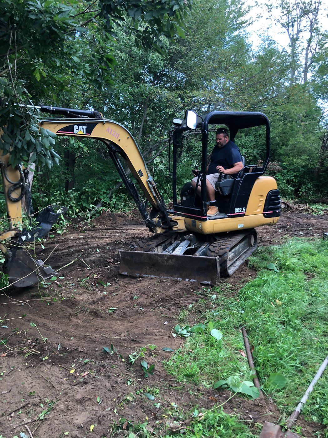 a man is operating a small excavator in a yard .