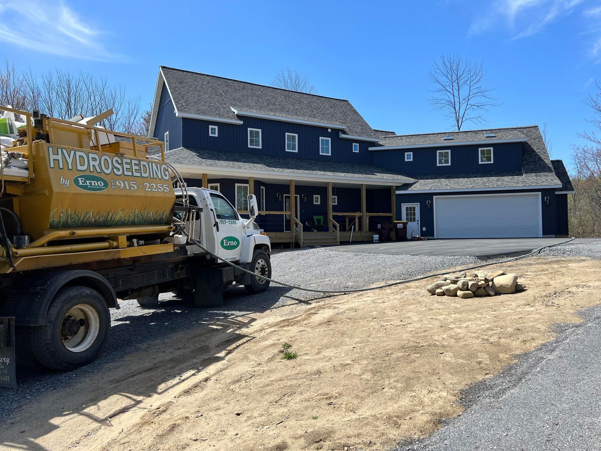 Erno hydroseeding truck is parked in front of a newly built blue house .