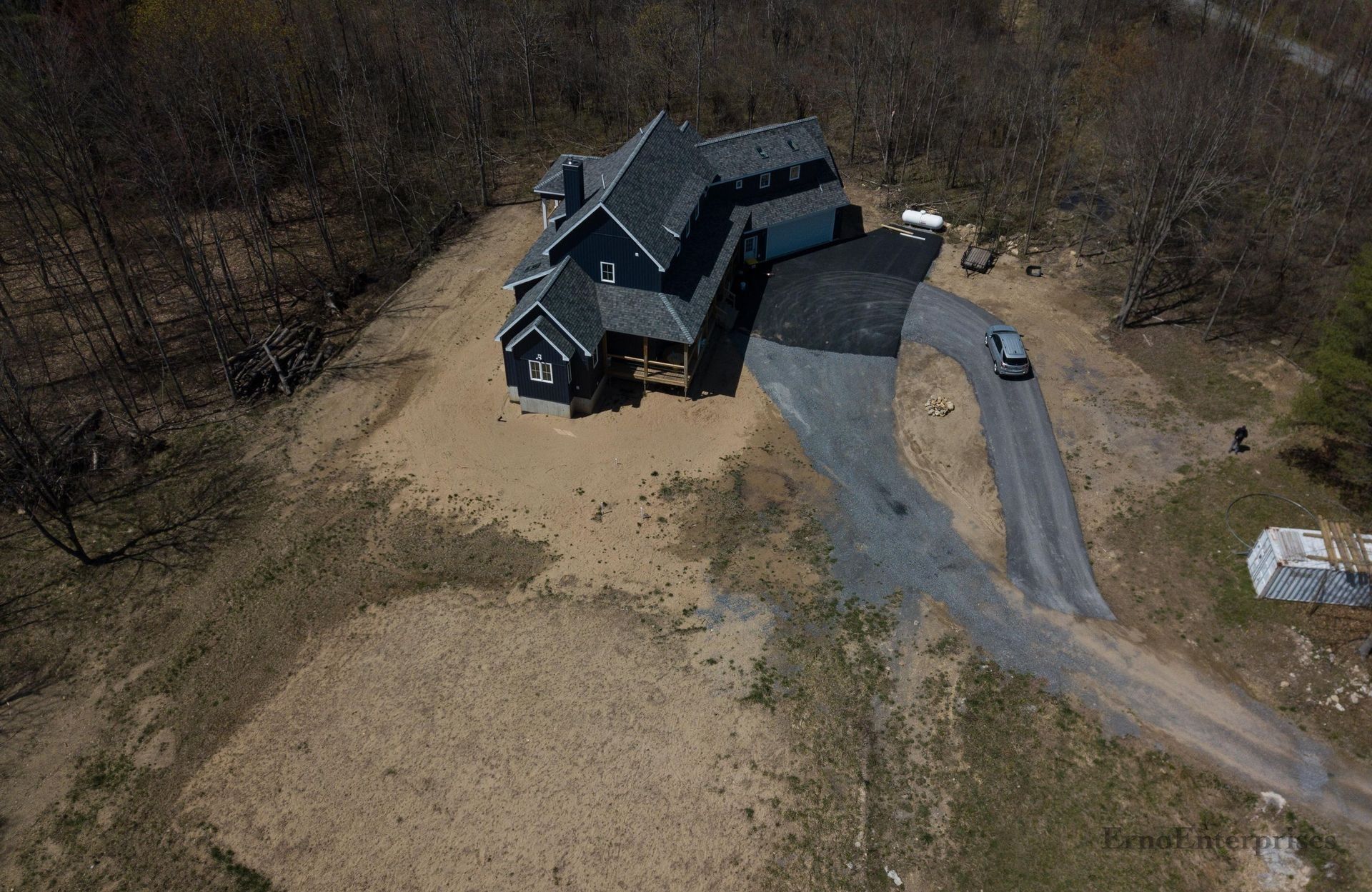 an aerial view of a house in the middle of a field surrounded by trees .
