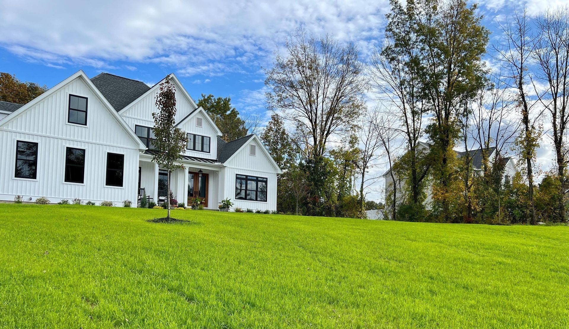 a large white house is sitting on top of a lush green lawn.