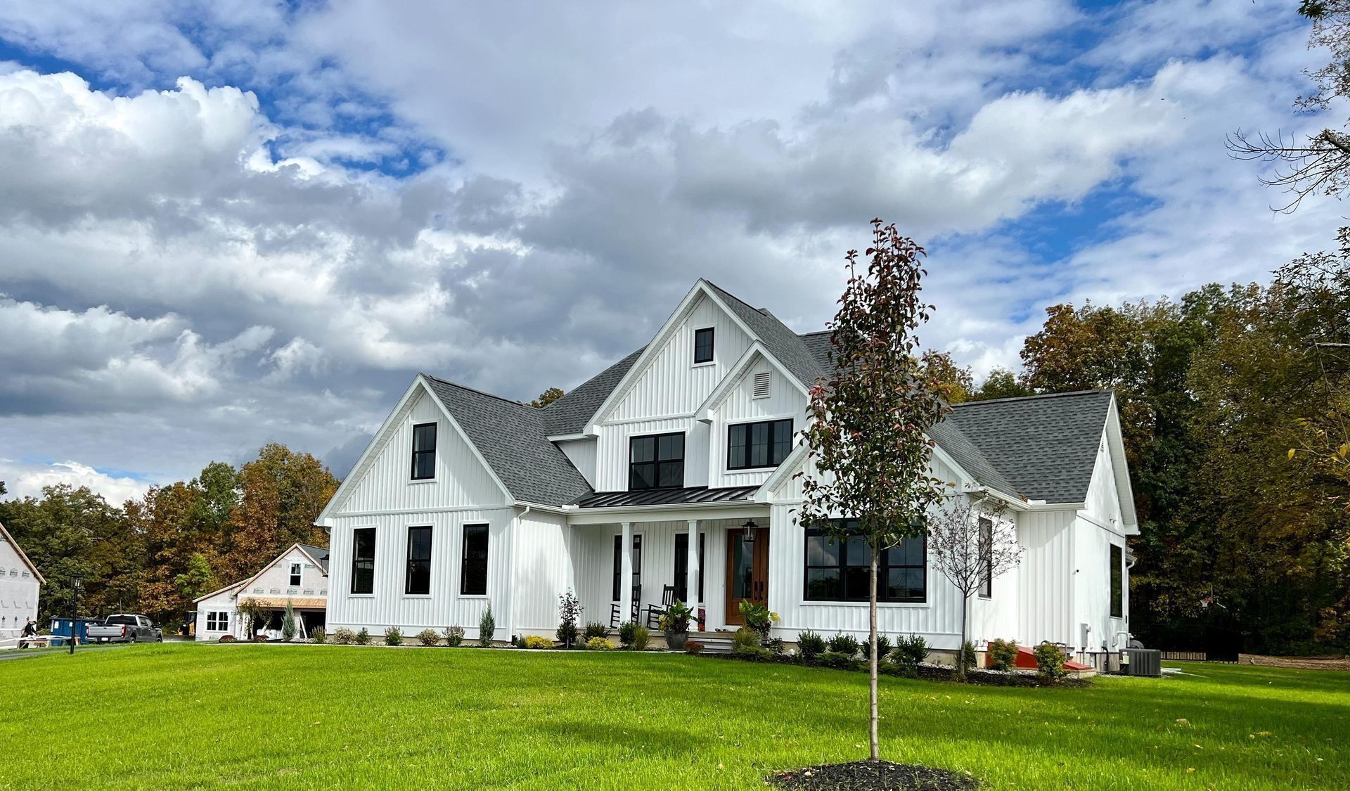 a large white house with a black roof is sitting on top of a lush green field .