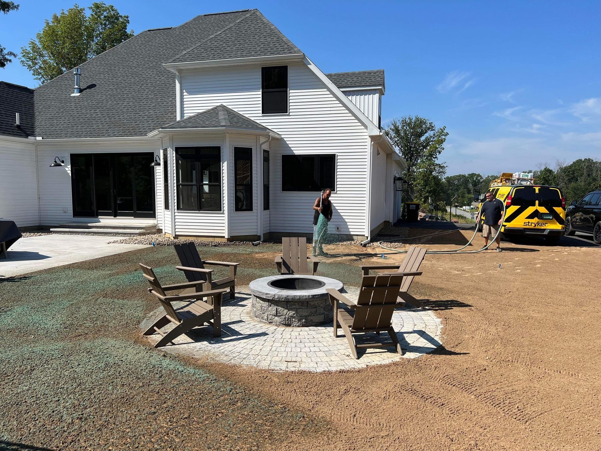 a white house with a fire pit and a newly hydroseeded back yard.
