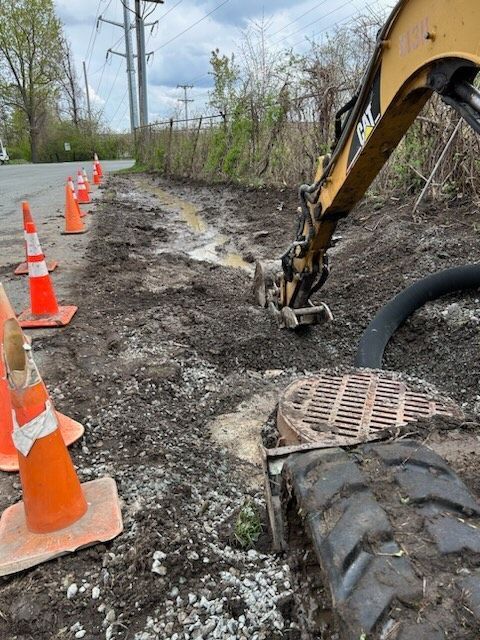 a cat excavator is digging a hole in the ground for a drainage project