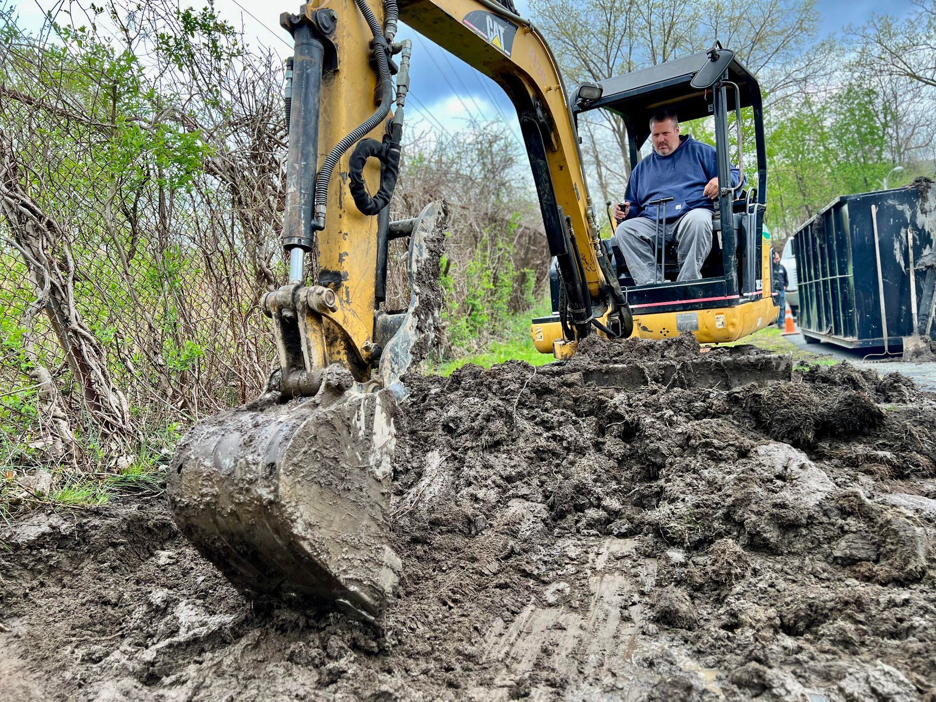 a worker is operating a small excavator as part of a grading and excavating job .