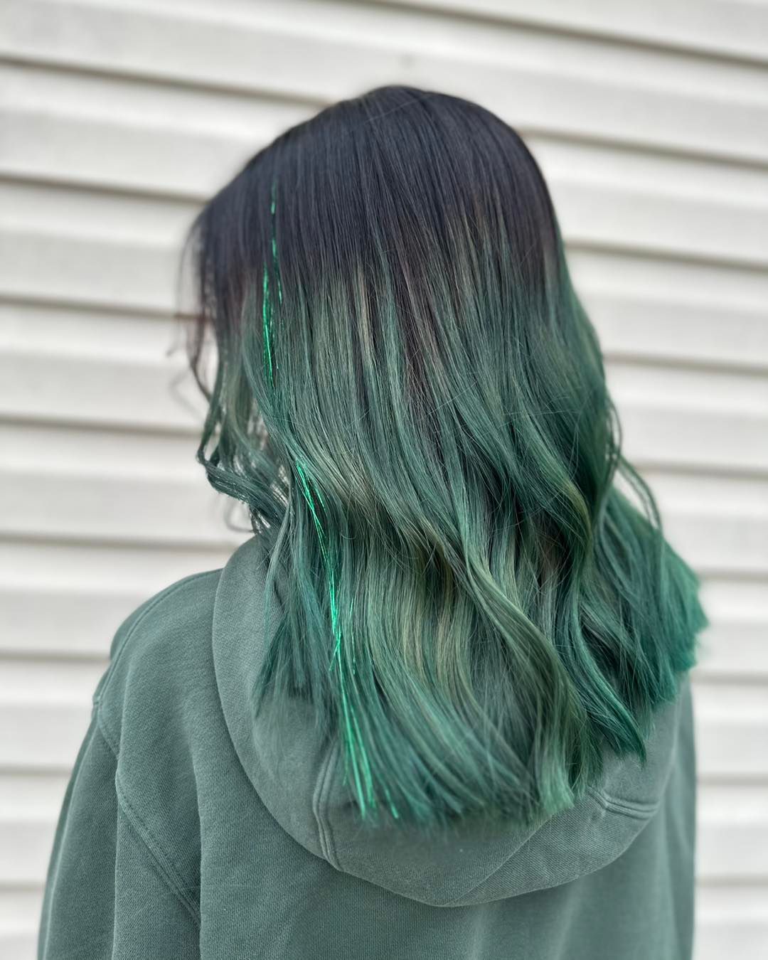 Woman with black to teal ombre wavy hair.