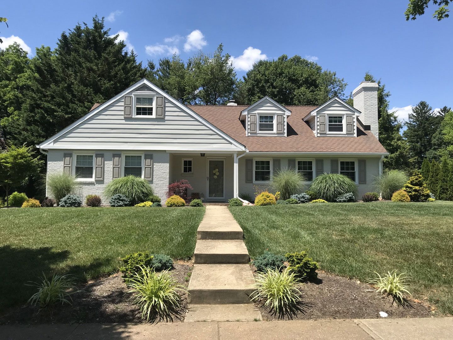 A white house with a brown roof and a walkway leading to it