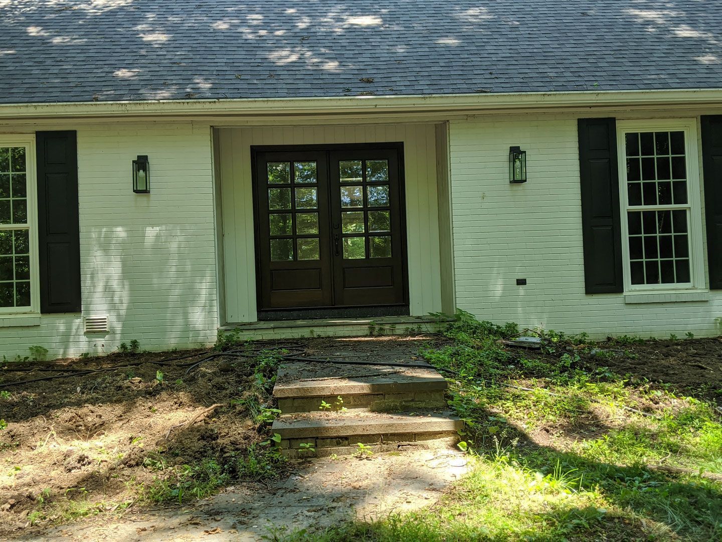 A white house with black shutters and stairs leading up to the front door.