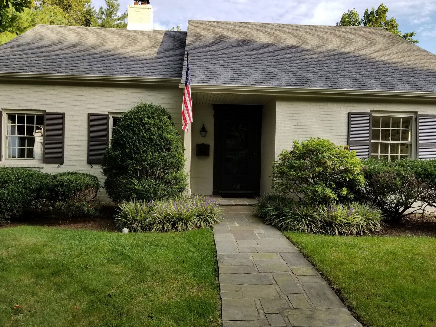 A white house with a black door and a flag in front of it