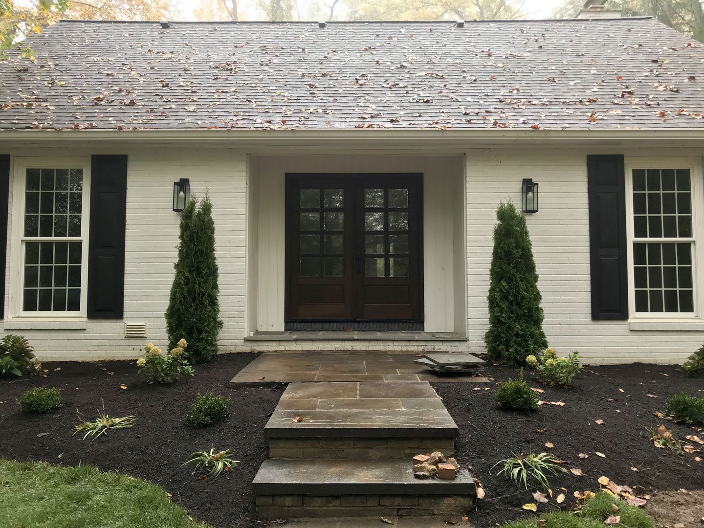 The front of a white house with black shutters