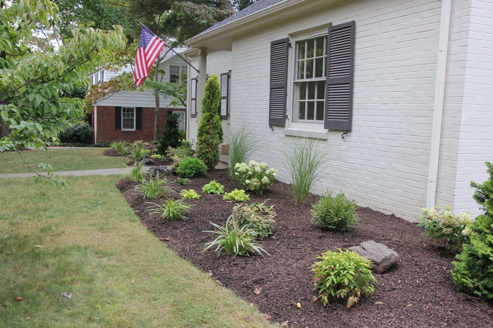 A white brick house with a flag flying in front of it.