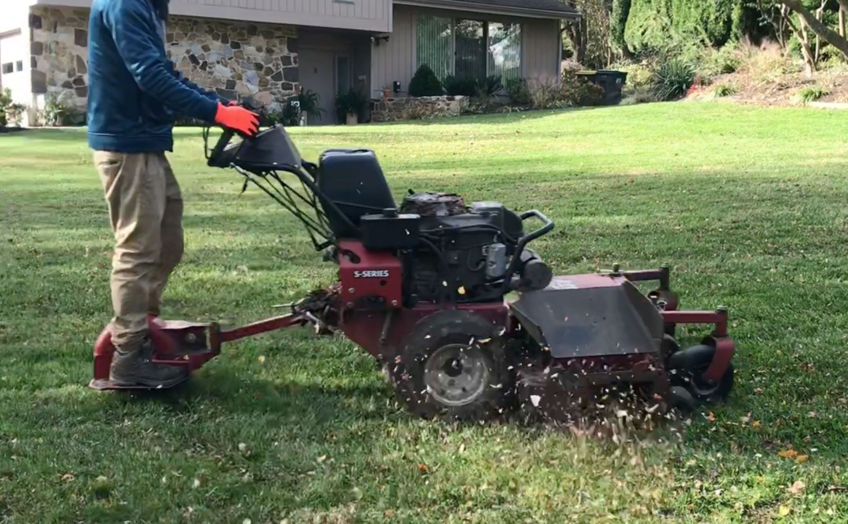 A man is using a lawn mower on a lush green lawn.