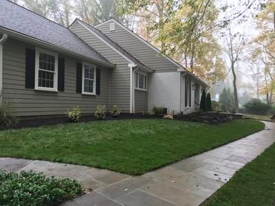 A house with a lush green lawn and a sidewalk in front of it.
