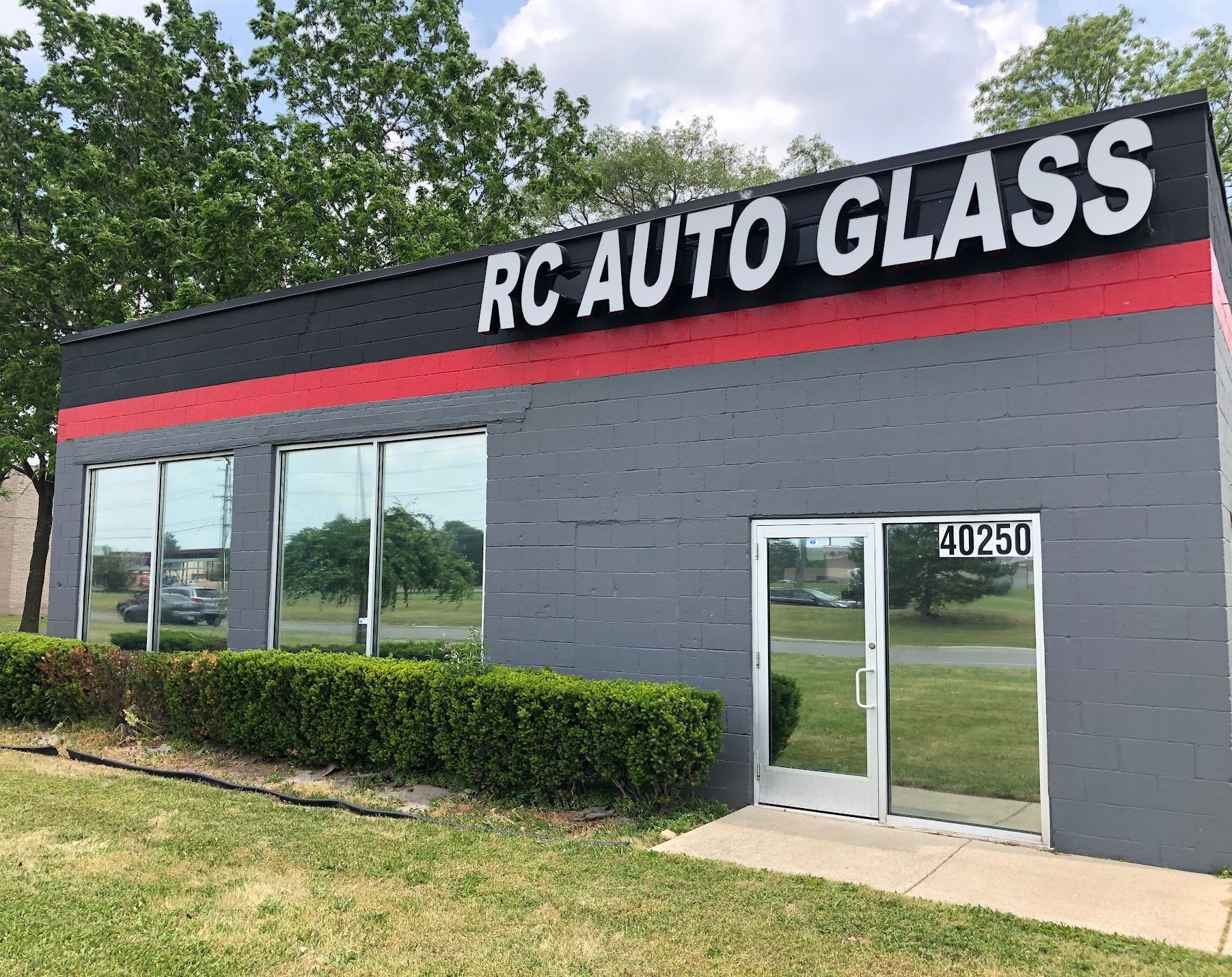 RC Auto Glass storefront with gray facade, red stripe, glass doors and windows, and address 40250.