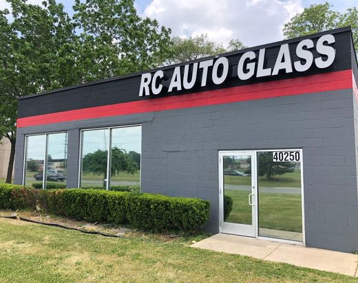 RC Auto Glass storefront with gray facade, red stripe, large windows, and glass door