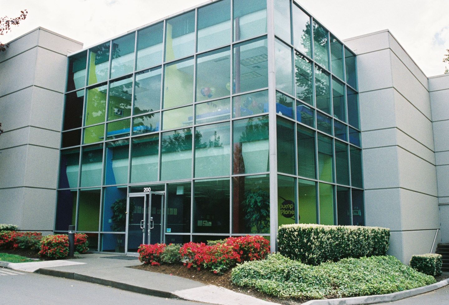 Modern office building with large glass windows, door, and landscaped greenery.