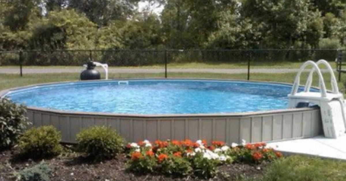 Round above-ground pool with blue water, white ladder, and beige siding surrounded by greenery.