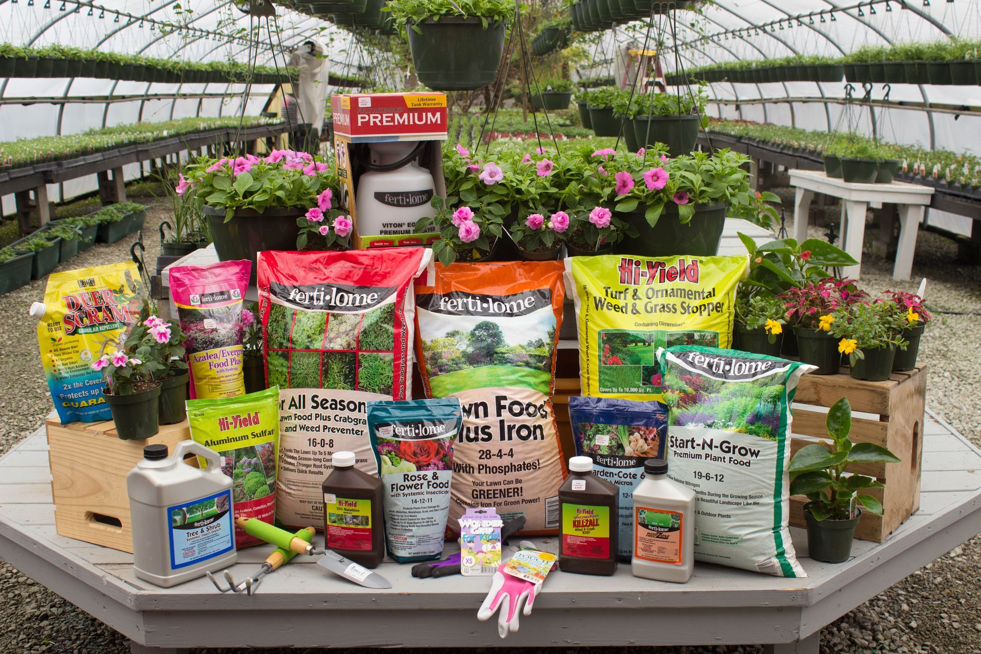 Various gardening products displayed on a table in a greenhouse setting.