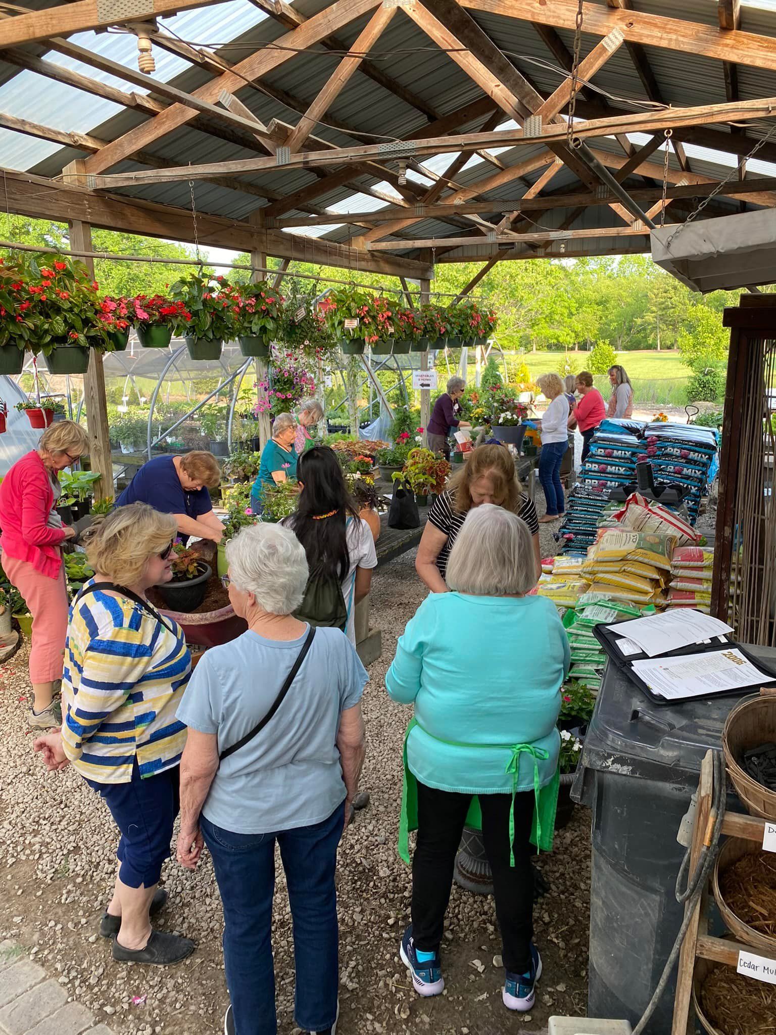 People browsing and shopping for plants at an outdoor garden center.