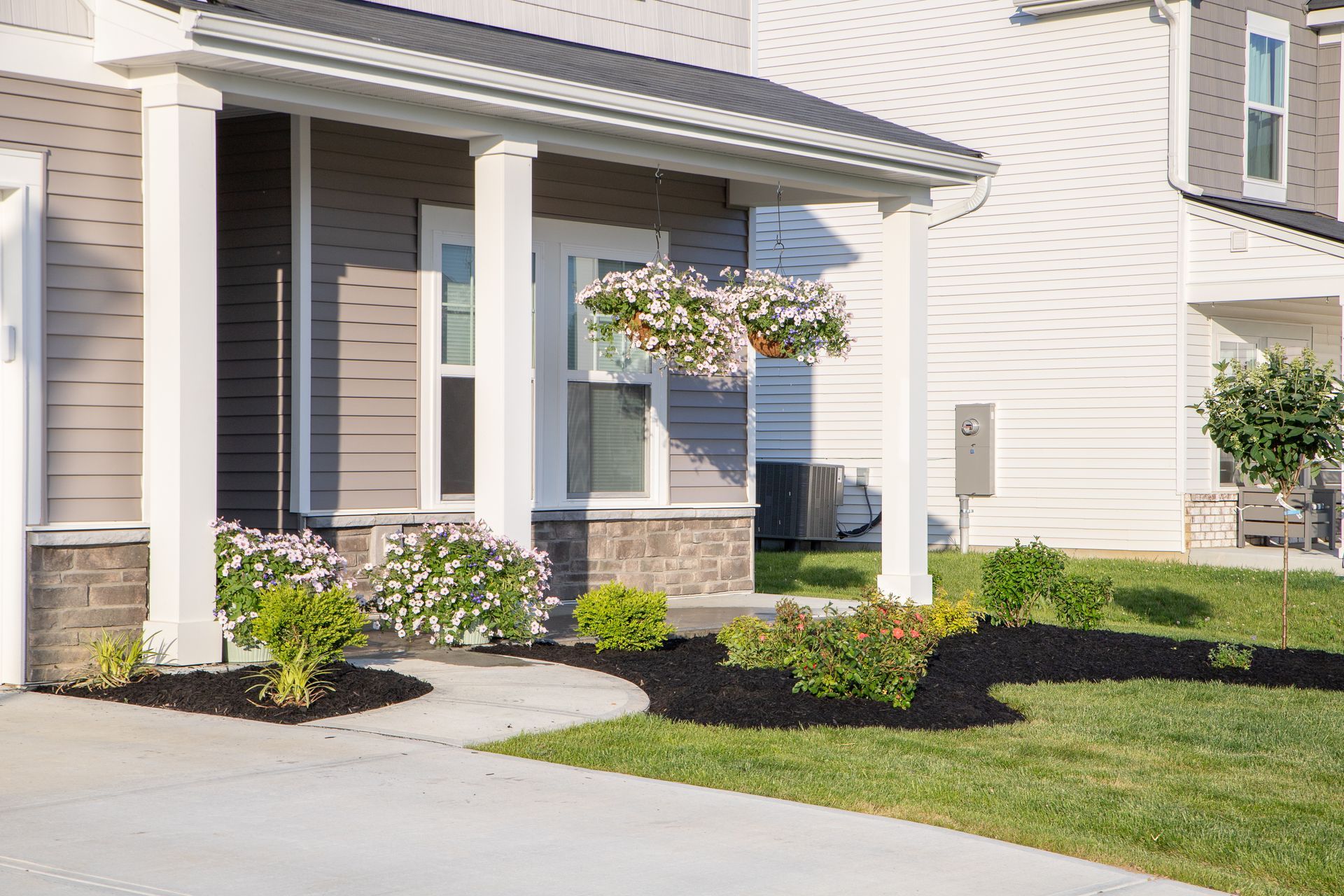 Front porch with hanging flower baskets and landscaping.