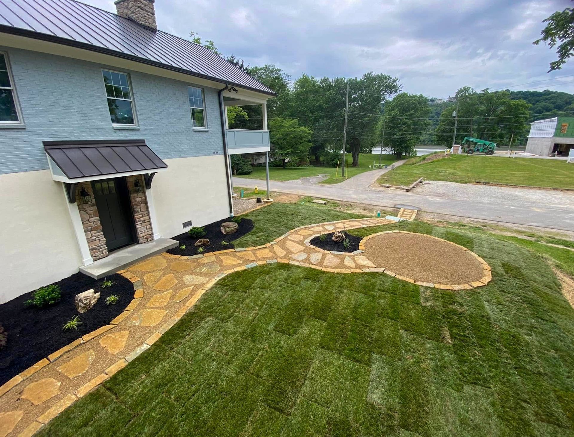 Exterior of a blue and beige house with a stone pathway and new lawn.