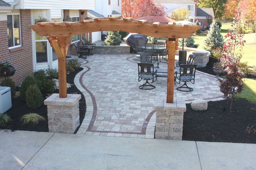 Patio with pergola, brick pavers, seating, and landscaping; view from above.