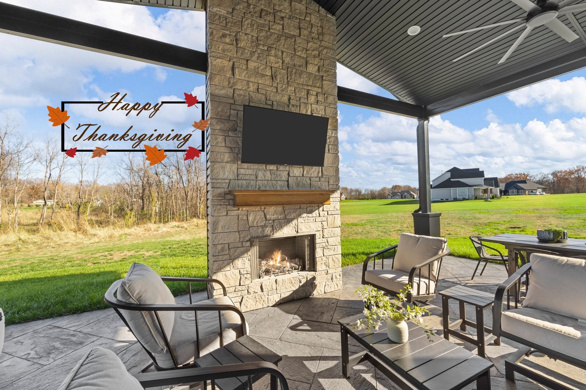 Outdoor patio with fireplace, TV, seating, and scenic view, framed with 