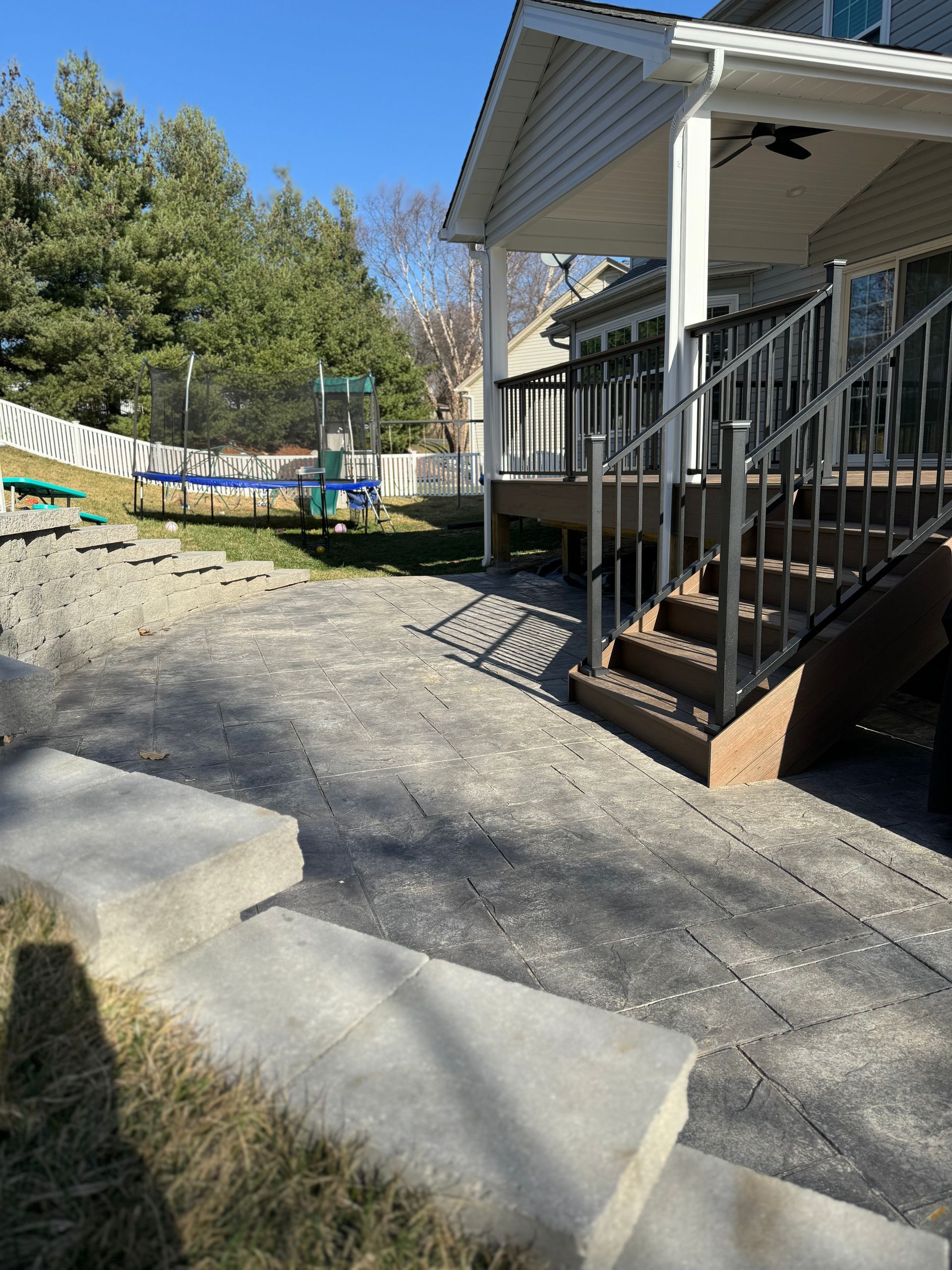 Backyard with a patio, deck with stairs, and a playset in the distance.