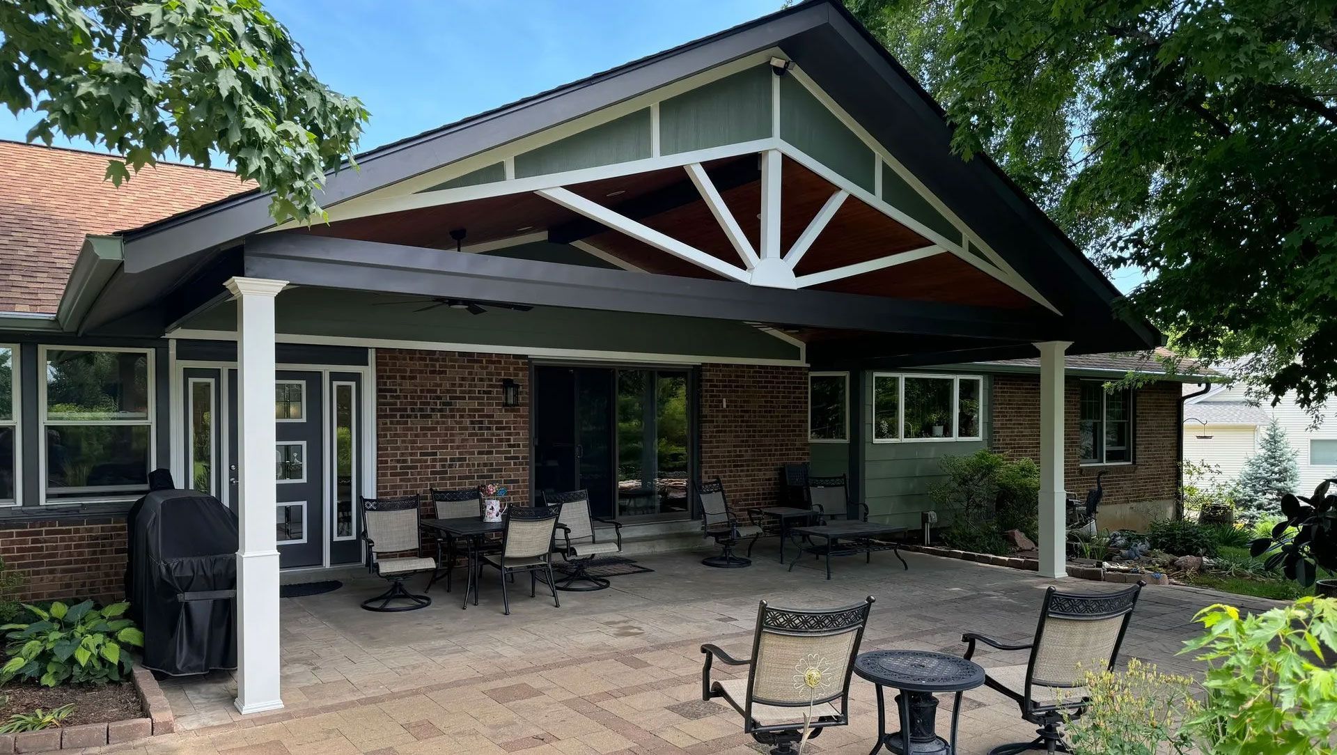 Backyard patio with black roof, brick wall, and outdoor seating.