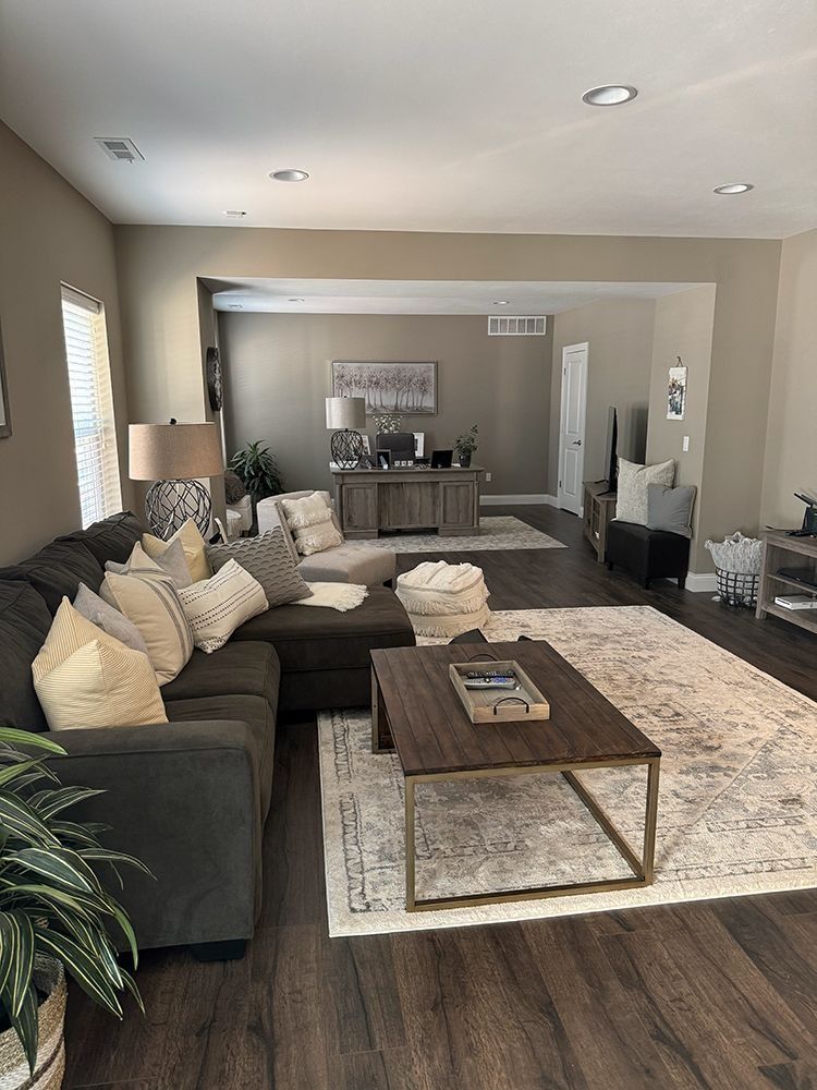Living room with dark gray sectional, beige rug, and dark wood coffee table. Neutral color palette.
