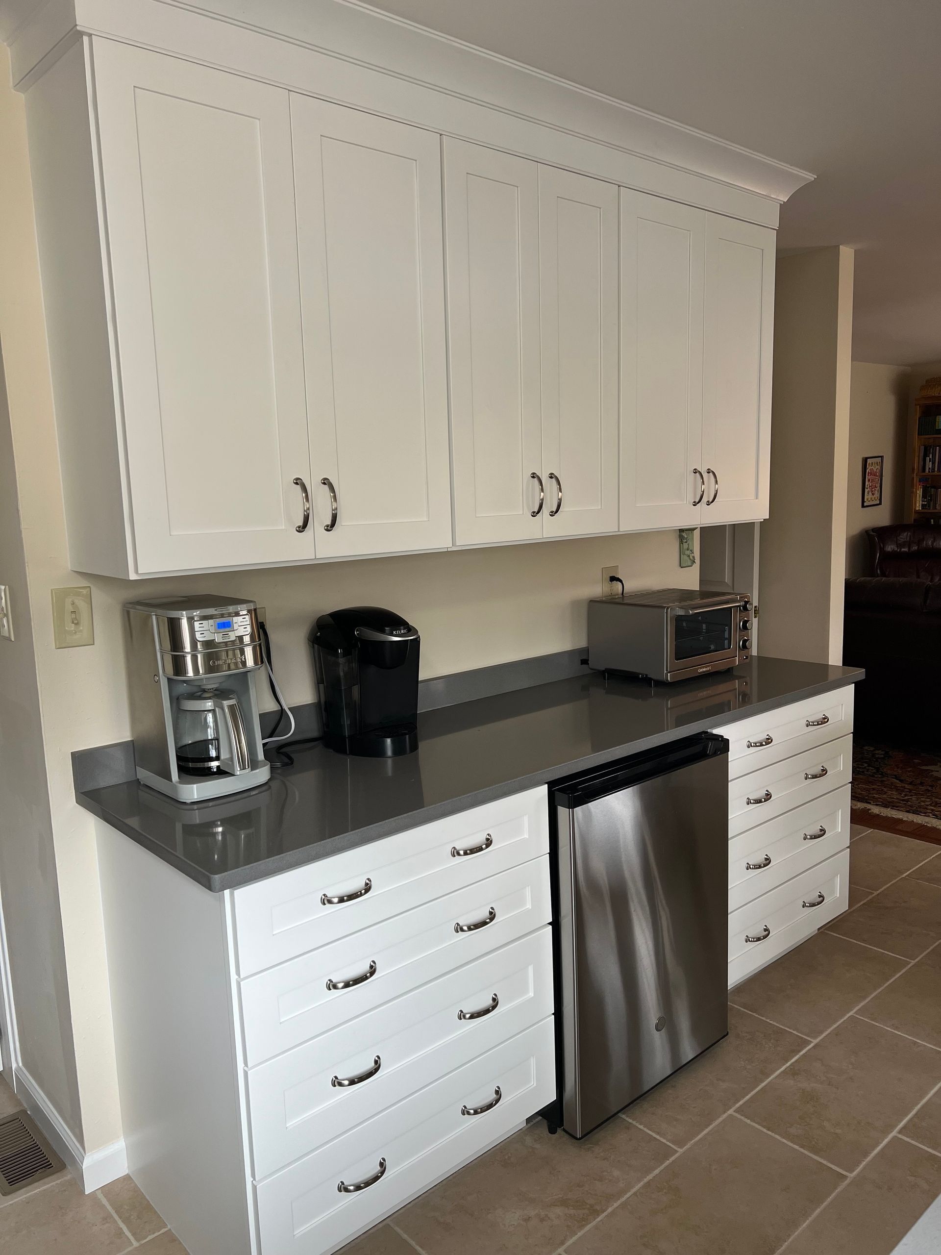 White kitchen cabinets with dark countertop, built-in dishwasher, and drawer units.