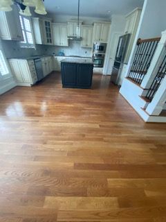 A kitchen with hardwood floors , white cabinets and stainless steel appliances.