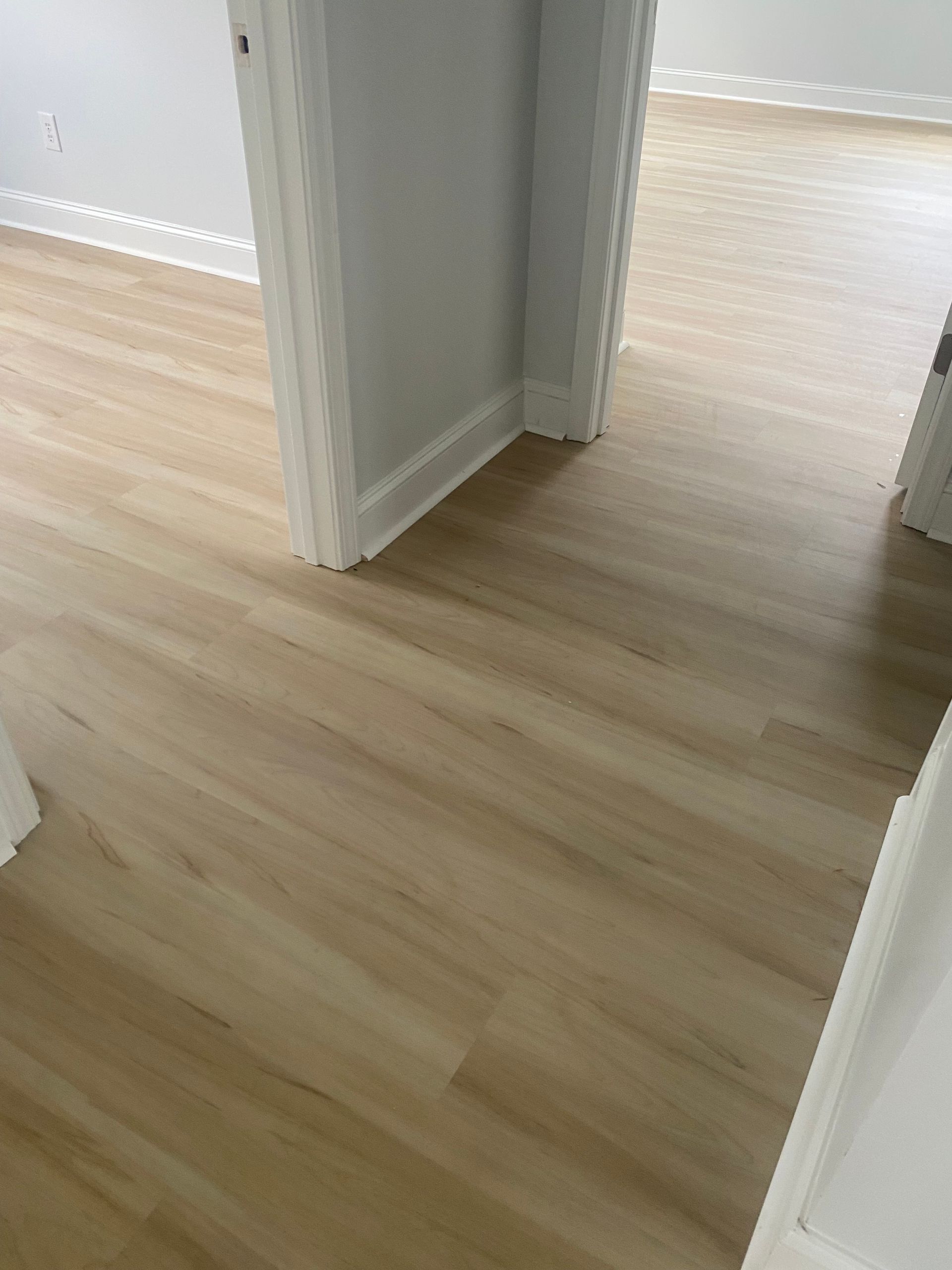 A wooden floor in a room next to a door.