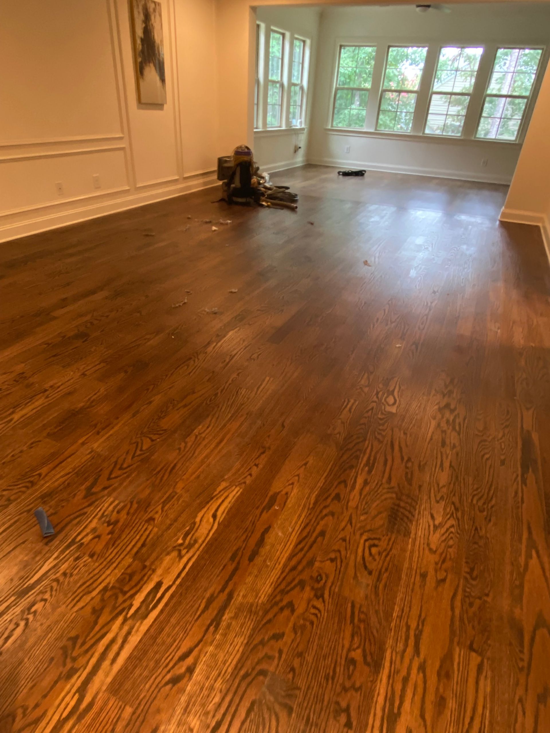 Dark stained hardwood floors in a room with white trim and windows, a small piece of art on the wall.