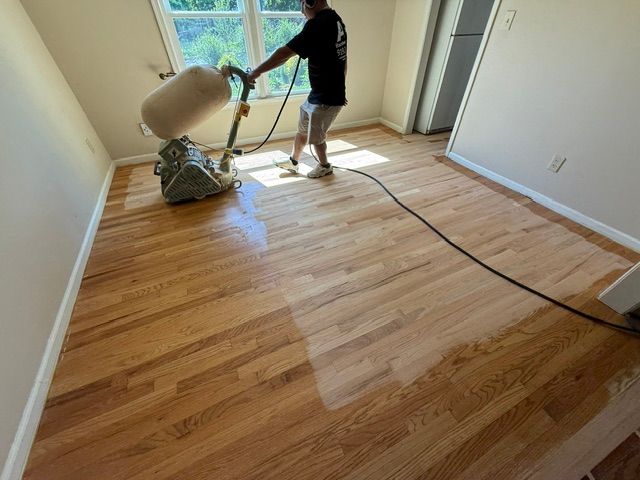 A man is sanding a wooden floor with a machine