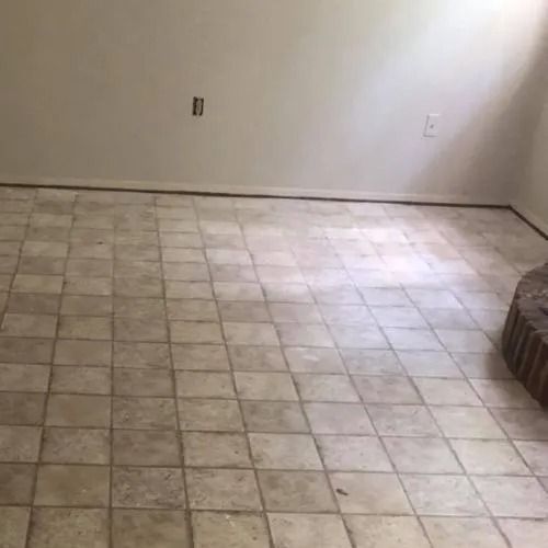 An empty room with a tiled floor and a fireplace.