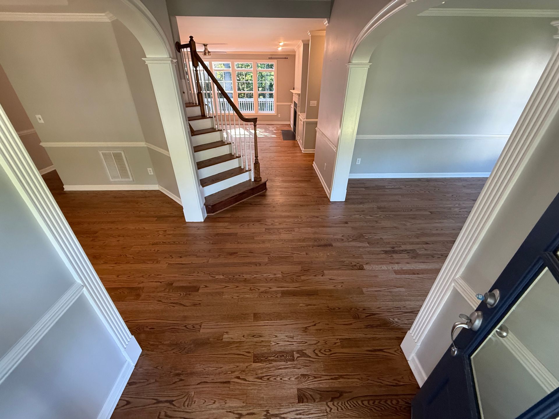 A hallway with hardwood floors and stairs in a house.