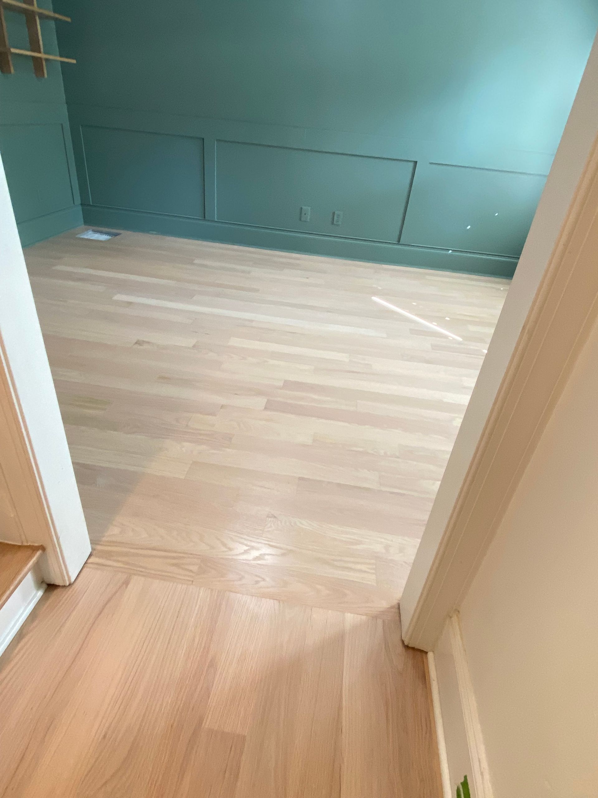 A room with a wooden floor and stairs leading up to it.