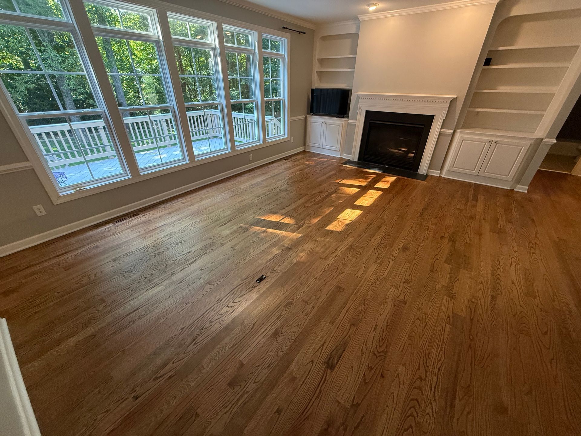 An empty living room with hardwood floors and a fireplace.