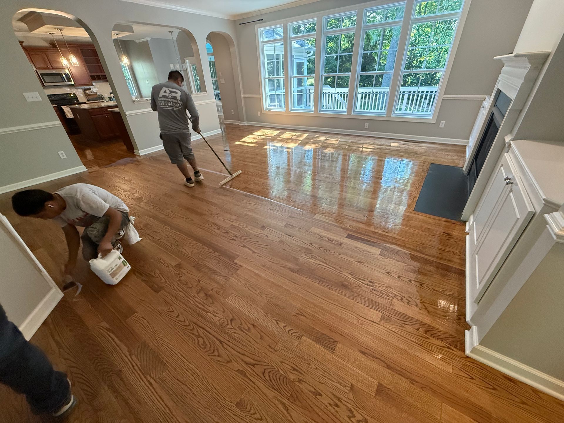 A man is cleaning a hardwood floor in a living room.