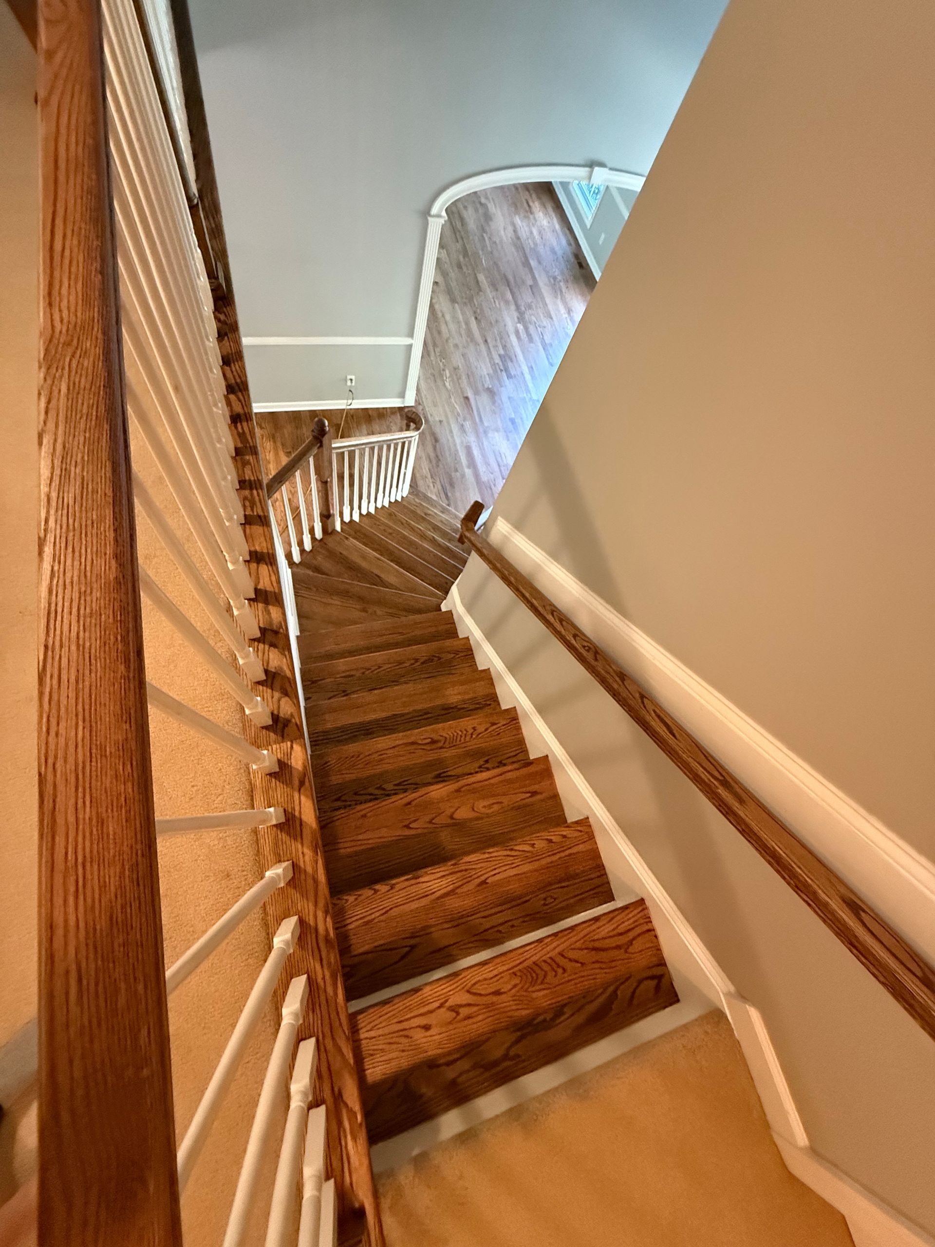 A wooden staircase with a white railing leading up to the second floor of a house.